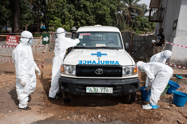 Photo of men in PPE suits washing an ambulance during a training in Sierra Leone. Credit: Joshua Yospyn