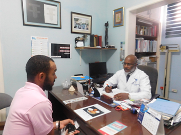 Photo of Williams speaking with a doctor across a desk.