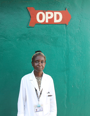 Photo of a female doctor standing underneath a sign that says OPD