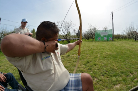 Photo of Marius pointing a bow and arrow at a target.