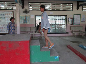 Photo of Sum Srey Norng walking up stairs with her prosthetic