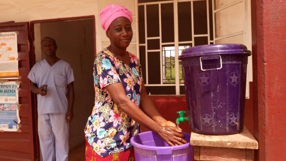 Zainab Fonafah washes her hands in front of the health facility.
