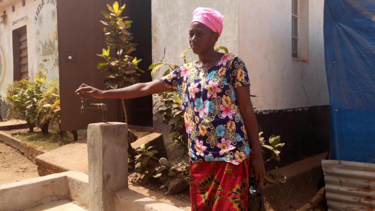 Zainab and one of the taps in her community.
