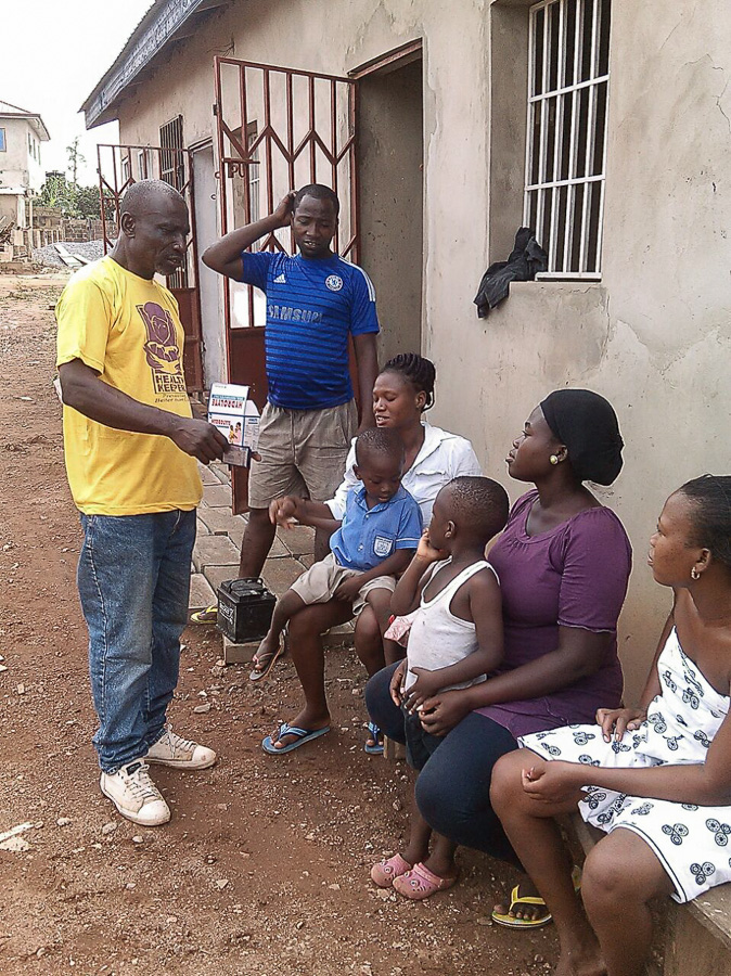 Photo of Nana Ohene Kwatia speaking with people outside their home.