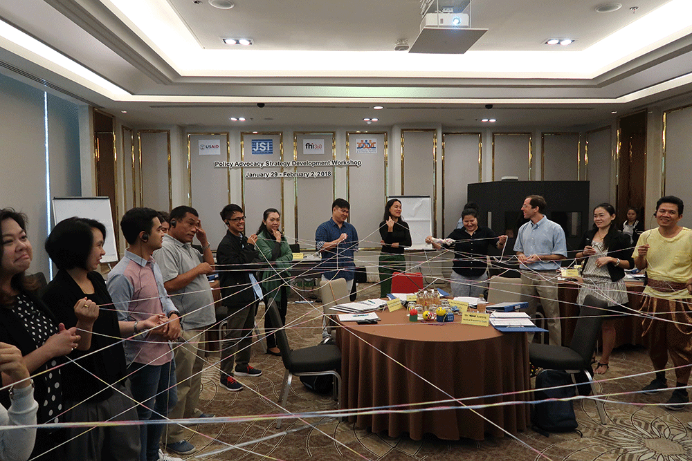 Workshop participants hold string creating a web.
