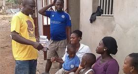 Photo of Nana Ohene Kwatia speaking with people outside their home.