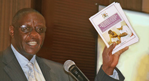 Photo of Dr. Nathan Kenya Mugisha, Director of Clinical Services, Uganda Ministry of Health, holding the Addendum to Section 3.8 Family Planning Service Standards in the Uganda National Policy Guidelines and Service Standards for Sexual and Reproductive Health allowing injectable contraceptive provision by trained CHWs. © FHI 360